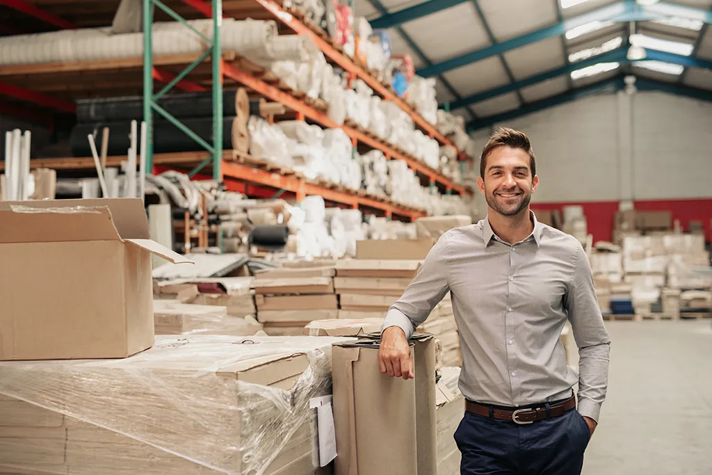 Warehouse manager leaning on packages smiling
