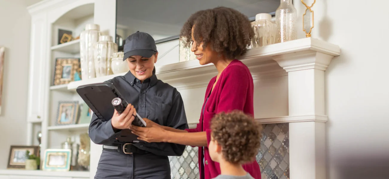 An Arrow Environmental Services technician reviewing a PestFree365 protection plan with a Florida homeowner and her son.