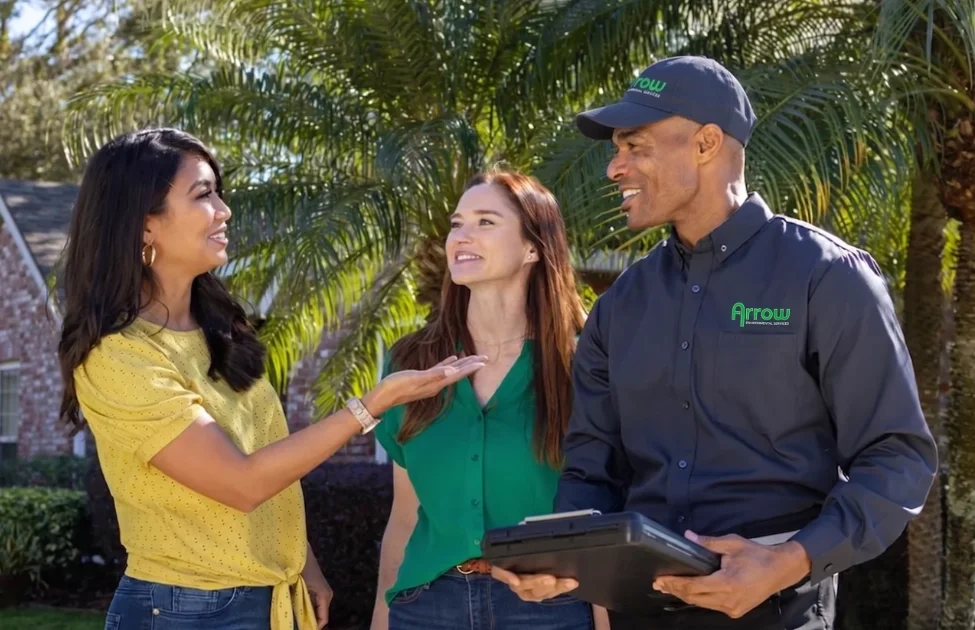 A friendly Arrow Environmental Services technician consulting with a Florida homeowner and her son during a residential pest inspection.