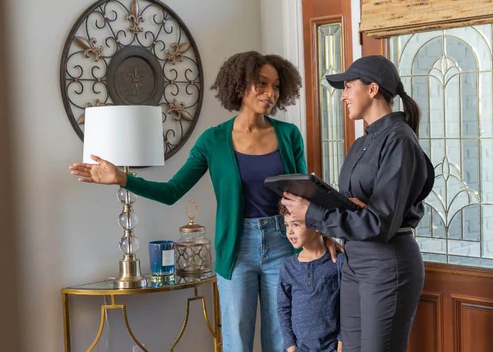 A friendly Arrow Environmental Services technician consulting with a Florida homeowner and her son during a residential pest inspection.