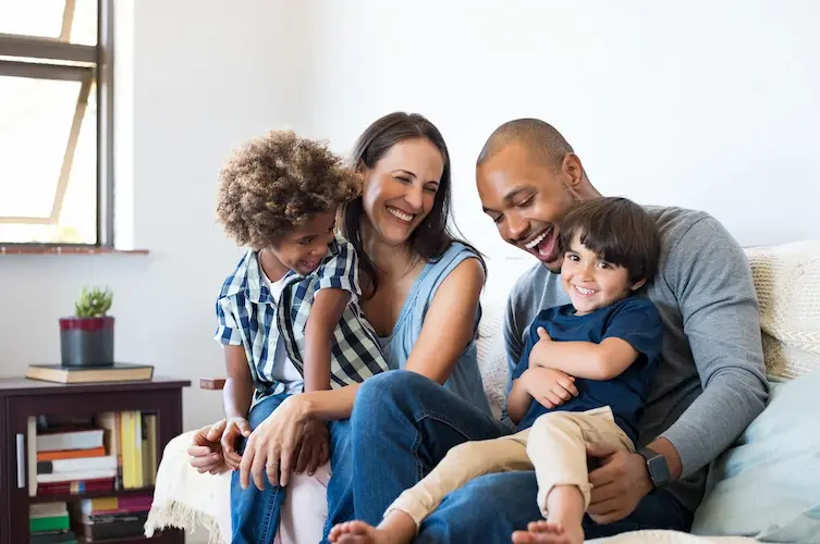 Here are three separate alt text options for this family-focused image for Arrow Environmental Services: Option 1: Service Focus (Primary) A happy family relaxing on a couch, enjoying the year-round protection of Arrow Environmental Services' PestFree365 program in Florida.