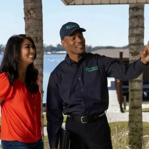 An Arrow Environmental Services technician pointing out potential pest entry points to a homeowner at a Florida lakeside residence.