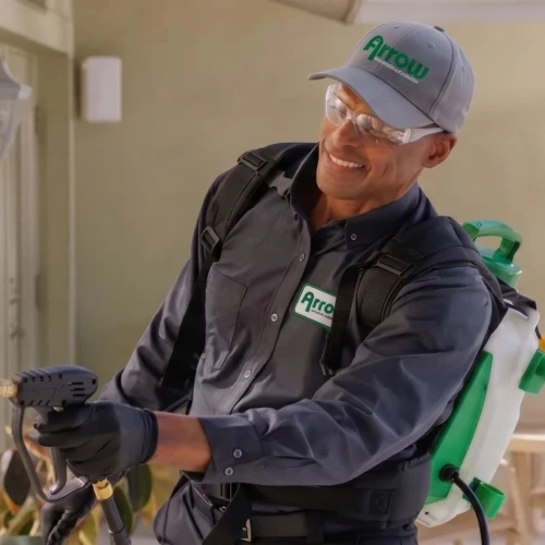 An Arrow Environmental Services technician applying a perimeter pest control treatment to the exterior windows of a Florida home.