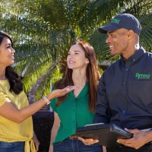 A friendly Arrow Environmental Services technician consulting with a Florida homeowner and her son during a residential pest inspection.