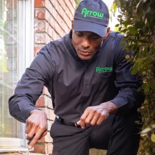 An Arrow Environmental Services technician inspecting a brick home’s foundation for pest entry points in the Florida area.